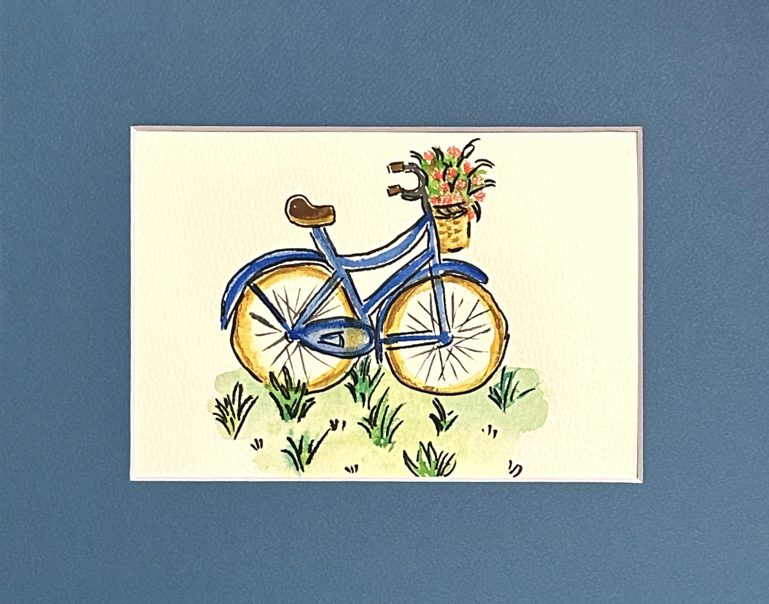 A blue bicycle with flower basket watercolor painting — a cornflower-blue cruiser in the grass with coral blooms on the handlebars, matted in slate blue, by Céline