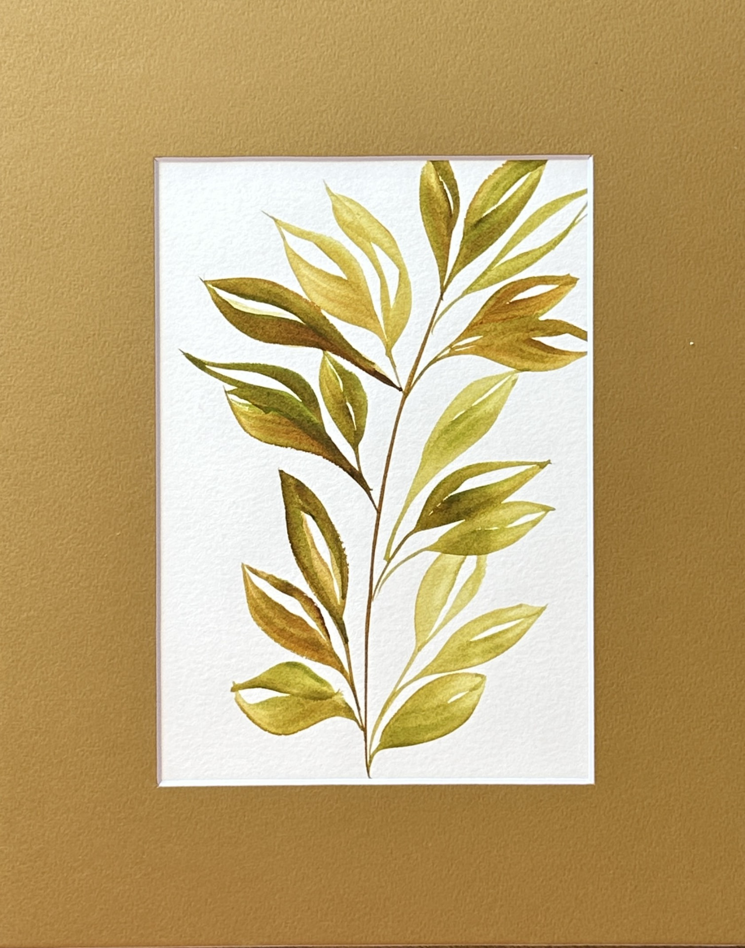 An olive green botanical watercolor painting of a leafy branch in sage, ochre and gold, matted in warm gold, by Céline